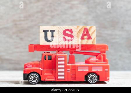 Red fire truck hold letter block in word USA (United states of America) on wood background Stock Photo