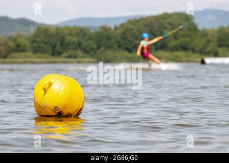 A yellow buoy is floats on a surface of water in a lake with a surfer on a background. Stock Photo