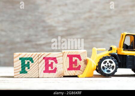 Toy bulldozer hold letter block e to complete word fee on wood background Stock Photo