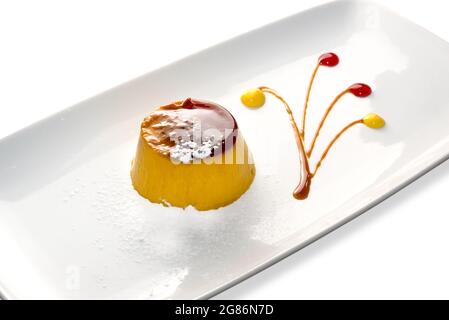 Creme caramel custard pudding with powdered sugar on white plate isolated in white, copy space Stock Photo