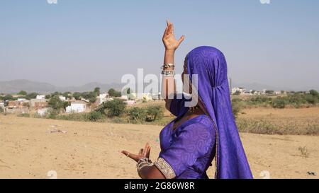 Young Indian female in a purple traditional dress dancing in an outdoor place Stock Photo