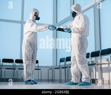 lab technicians in protective suits shaking hands. Stock Photo