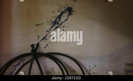 A dirty white wall with blue paint splashes with a bundle of dark gray pipes. Meant as background Stock Photo