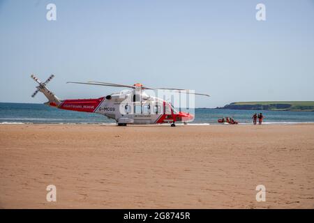 Lunan Bay Beach, Angus, Scotland, UK, 17th of July 2021: Major rescue operation carried out by the coastguard and RNLI, after a mum and daughter drifted out to sea on their inflatable dinghy in strong winds today at Lunan Bay Beach. An offshore supply vessel, which was nearby, also launched it FRC to assist with the rescue. In this photo you can see the coastguard helicopter crew walking back to their helicopter, and the inshore RNLI lifeboat lunching from the beach. (Credit:Barry Nixon/Alamy live news) Stock Photo