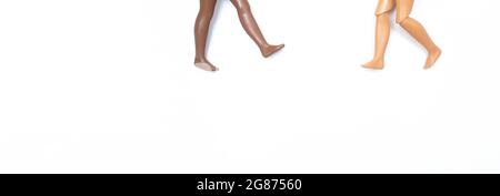 Two pair of toy dolls legs going to each other on white background. Different skin tones and races. Stop racism. Concept of Diversity and unity Stock Photo
