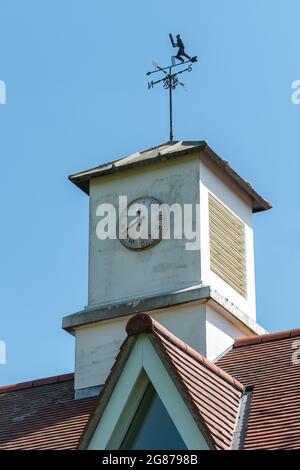 Clock tower and cricketer weather vane on the sports or cricket pavilion in the Hampshire village of Ropley, England, UK