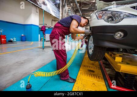 Kostanay,Kazakhstan,May14,2012:Saryarkaavtoprom auto-building plant. Ssangyong cars assembling. Workers on conveyor line. Installing wheels arches. Stock Photo