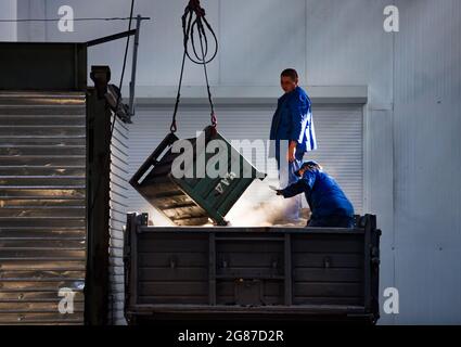 Kostanay,Kazakhstan,May14,2012:AgroMashHolding auto-building plant. Two workers unloading factory waste in truck. Beautiful sunlight. Stock Photo