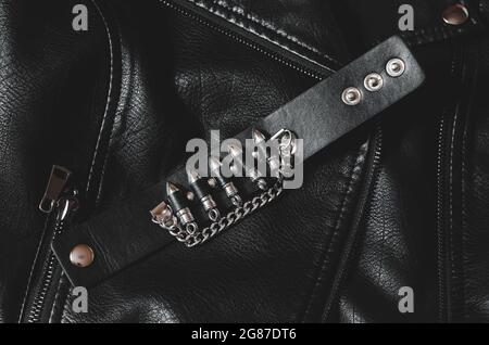 Black leather bracelet with bullets on a leather jacket. Stock Photo