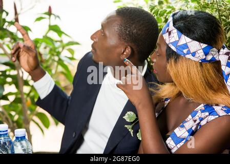 beautiful happy couple sitting at table, having hand gesture shows something while looking away during a romantic dinner at the restaurant outside Stock Photo