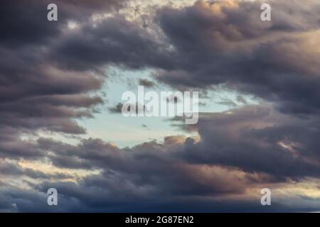 Stormy clouds with blue sky hole during sunset. Stock Photo