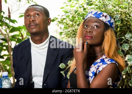 beautiful happy couple sitting at table, talking, and thinking while looking away during a romantic dinner at the restaurant outside Stock Photo