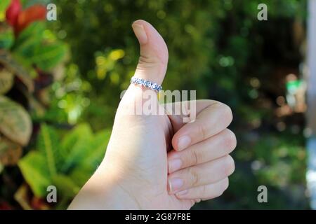 A woman's hand giving a thumbs up with a ring on her thumb. Stock Photo