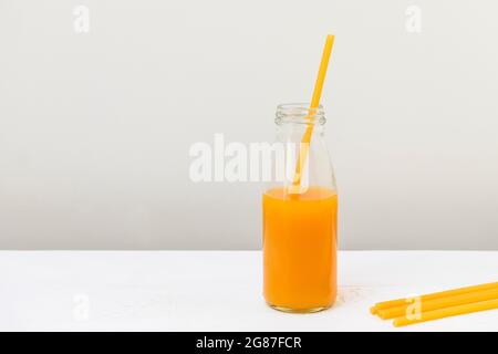 Pasta straw in a glass bottle with peach juice, zero waste concept Stock Photo
