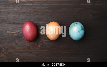 Three Easter eggs on wood table background. Flat lay. Stock Photo