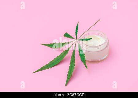 Cannabis-infused cosmetics concept. Bottle of cream with hemp leaf on soft pink background with copy space Stock Photo