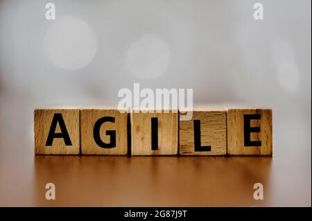 The ord 'Agile' spelled out with wooden blocks, set against a softly blurred background. This image captures the essence of flexibility and innovation Stock Photo