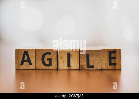 The ord 'Agile' spelled out with wooden blocks, set against a softly blurred background. This image captures the essence of flexibility and innovation Stock Photo