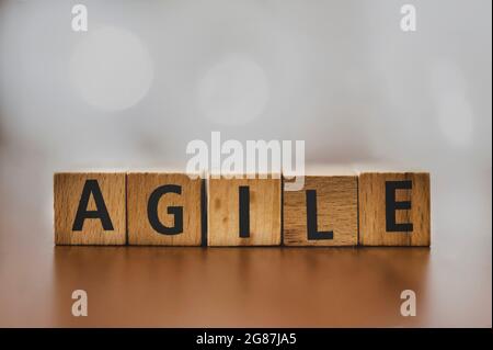 The ord 'Agile' spelled out with wooden blocks, set against a softly blurred background. This image captures the essence of flexibility and innovation Stock Photo