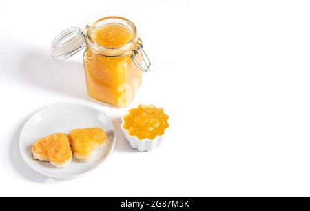Yellow jam and toast hearts on a white background. Fruit confiture in a jar. Space for text. Stock Photo