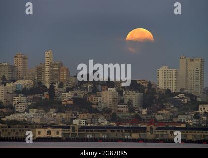 partial eclipse of full blood super moon setting over the outskirts of San Francisco, CA. in early hours of dawn Stock Photo