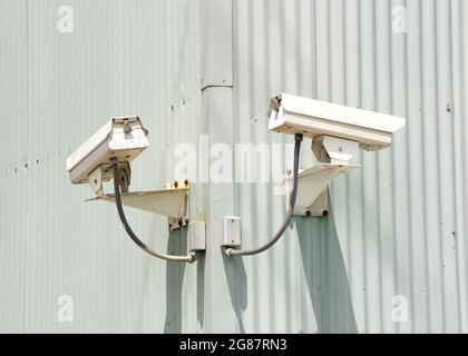 Security cameras on the corner of an industrial building. Hard wired into the building. Stock Photo