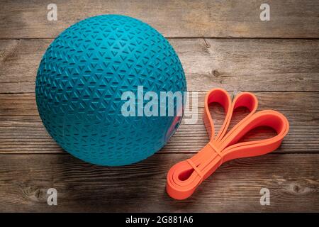 heavy rubber slam ball filled with sand and resistance band  on a rustic wooden deck, exercise and fitness concept Stock Photo