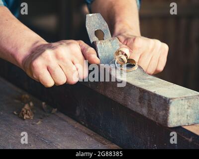 The carpenter using a manual plane for woodworking in his workshop Stock Photo