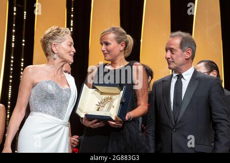 Sharon Stone (l-r), Julia Ducournau and Vincent Lindon pose with the Palme d'Or 'Best Movie Award' for 'Titane' at the closing ceremony during the 74th Annual Cannes Film Festival at Palais des Festivals in Cannes, France, on 17 July 2021. Stock Photo