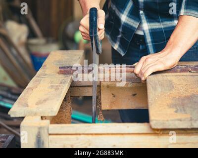 The carpenter using a hand saw for woodworking in his workshop Stock Photo
