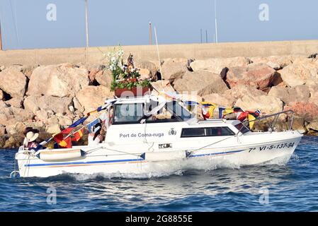 A view of a boat leading with a statue of the Virgen del Carmen during the seafaring procession in Vendrell. Every year on July 16 a religious festival is celebrated in honor of the Virgen del Carmen, patron saint of sailors and fishermen, although the celebration is on July 16, the procession is held on the weekend so that more people can attend the celebration. The statue of Virgin, is carried by a group of people taking it to a boat leaving during the procession through the waters of the sea near the port followed by several boats. Stock Photo