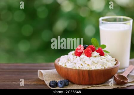 yogurt in glass and cottage cheese with fresh berries on table outdoors Stock Photo