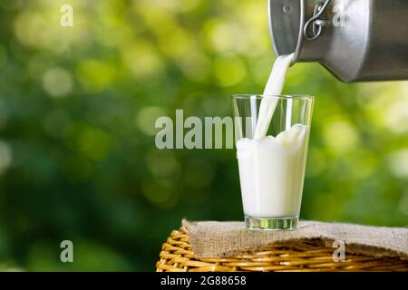 milk pouring from metal can into glass Stock Photo