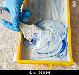 Cropped view of hand wearing gloves using paint brush and paint Stock Photo