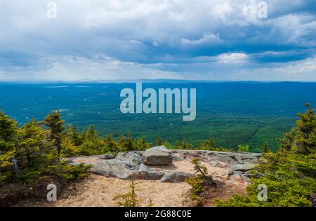 Western view from Mt. Kearsarge summit towards Lake Sunapee and Mt. Ascutney. Rocky granite outcrop and stunted spruce trees. Distant peaks and ridges Stock Photo