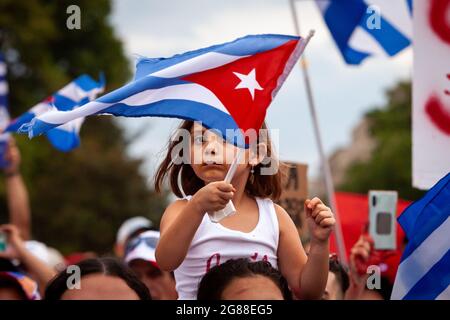 Washington, DC, USA, 17 July 2021.  Pictured: A young girl waves a Cuban flag while sitting on someone's shoulders.  Thousands gathered in front of the White House in solidarity with the Cuban people.  Protesters demanded US intervention to free Cuba.  Credit: Allison Bailey / Alamy Live News Stock Photo