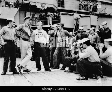 JOHN WAYNE on set location candid with Sailors taking photos of him on the flight deck of the aircraft carrier U.S.S. Philippine Sea during a break in filming of THE WINGS OF EAGLES 1957 director JOHN FORD screenplay Frank Fenton and William Wister Haines based on the life and writings of Frank W. ''Spig'' Wead Metro Goldwyn Mayer Stock Photo