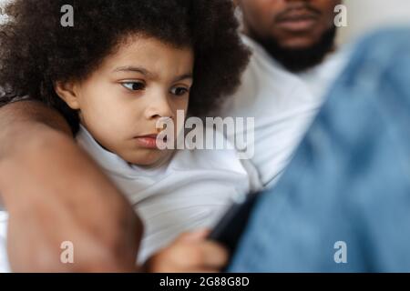 Black father and son using tablet computer while resting together at home Stock Photo
