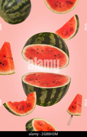 Ripe watermelon cut into pieces flying in the air. Floating, flying, levitating sliced fresh watermelon on trendy colored background. Creative and abs Stock Photo