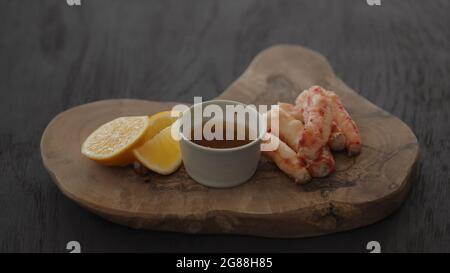 Slow motion gimbal shot of crab leg meat on a olive board with sweet lemon and dip sauce, 120fps Stock Photo