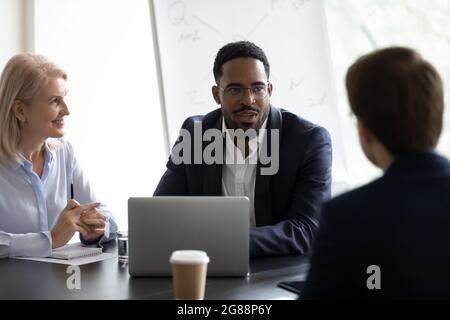 Confident mentor giving lecture to interns on corporate meeting Stock Photo