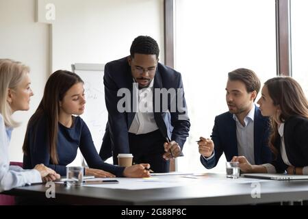 Serious African American team leader talking to employees Stock Photo