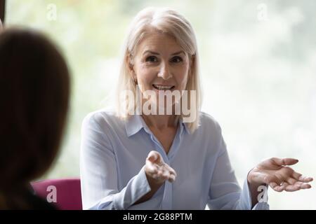 Happy confident mature businesswoman speaking, negotiating on deal at meeting Stock Photo