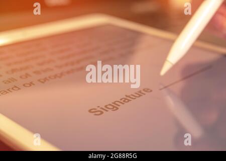 Signing the contract with digital signature on the tablet, close-up of document, stylus in hand, selective focus Stock Photo