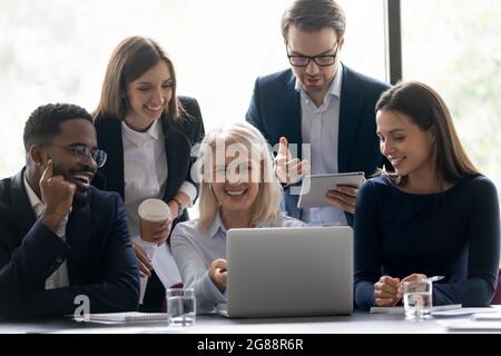 Happy senior mentor, coach teaching excited diverse interns Stock Photo