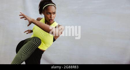 Young African woman doing stretching exercise. Athlete woman doing warm up workout against white background. Stock Photo
