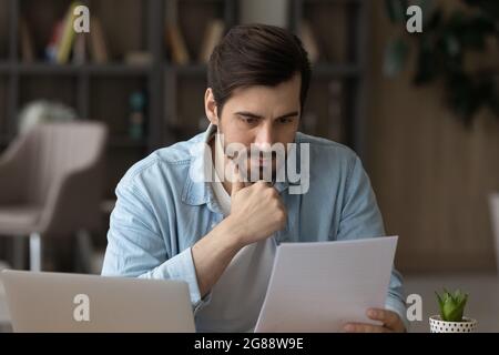 Thoughtful young businessman analyzing financial paper data. Stock Photo