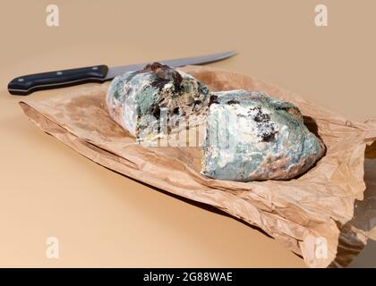 Green moldy bread on craft pack. Food waste concept. Minimalist style. Stock Photo