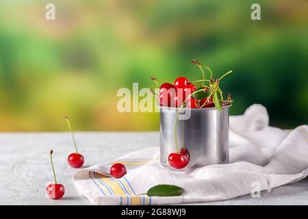 Freshly cut cherries berries in an iron mug outdoors Stock Photo