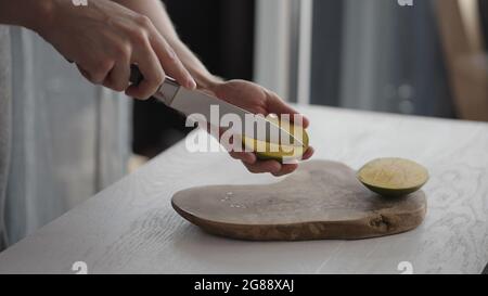Man cutting ripe mango on olive board on white oak table, wide photo Stock Photo